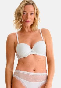Witte gevoerde beha met een stippenstructuur en verstelbare bandjes. Gecombineerd met doorschijnende bijpassende slipjes met kantafwerking en stippen.
