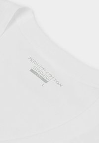Hvid bomulds t-shirt med rund halsudskæring, der har et label med teksten "Premium Cotton," "Intimissimi," og størrelse "L."