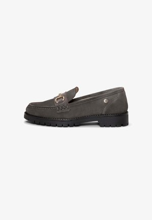 Mocasín de ante gris oscuro con suela negra gruesa, detalle de pieza metálica dorada en el empeine, costuras laterales y puntera redonda.
