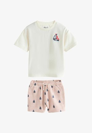 Kortærmet t-shirt i bomuld i cremefarve med grafik af en sejlbåd; kombineret med pinkternet shorts med små sejlbådsmotiver og elastisk taljebånd.