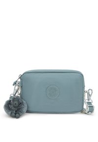 Blaues Nylon-Reißverschlussetui mit einem runden Logo, silberner Hardware und einem grauen Pom-Pom-Affenanhänger. Glatte Textur, rechteckige Form.