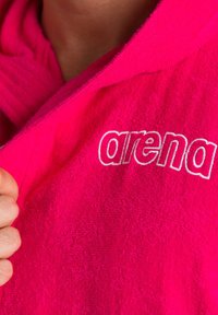 Accappatoio rosa brillante realizzato in tessuto di spugna testurizzato con il logo "arena" ricamato in bianco, dotato di cappuccio e apertura frontale.