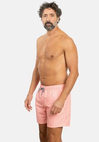 Shorts de baño rosa con un patrón sutil, cintura elástica y cordón. Hechos de una tela ligera, ideales para la playa.