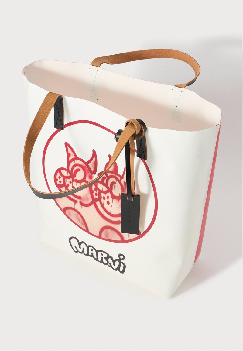 Weißer Jutebeutel mit rosa Innenfutter, braunen Ledergriffen, schwarzen Akzenten und einem kreisförmigen roten Grafikdesign mit verspielten Charakteren.