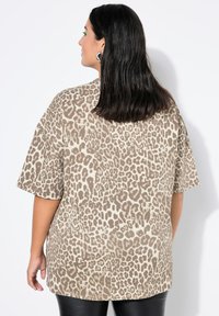 Oversized T-shirt met luipaardprint in beige en bruin, korte mouwen, zachte stof, ontspannen pasvorm, met een gebogen zoom en minimalistische stikdetails.