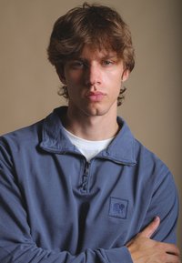 Námořnický zipový svetr s texturovaným povrchem, který má malé vyšívané logo slona na levé hrudi a vysoký límec.