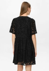 Rochie neagră cu mânecă scurtă, din material transparent, cu broderie florală, talie gathered și fustă evazată cu tiv ciufulit.