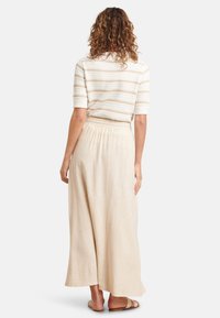 Lichtbeige lange rok van linnen met een relaxed fit, gecombineerd met een getextureerde witte en beige gestreepte top, met een ronde halslijn.