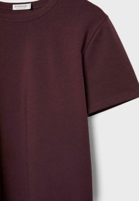 T-shirt bordeaux a maniche corte realizzata in morbido cotone. Presenta un collo a girocollo e un design semplice senza fantasie o accenti.
