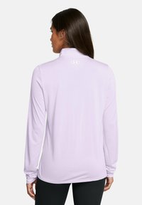 Light purple long-sleeve shirt with a high collar, smooth texture, and logo on the upper back. Fitted silhouette, paired with black leggings.