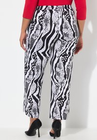 Zwart-wit gemusterde pantalons met een mix van strepen en abstracte vormen, voorzien van een elastische tailleband en een cropped ontwerp.