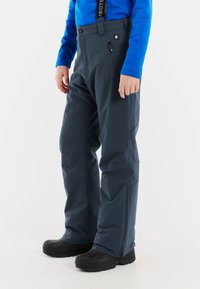 Donkergrijze skibroek van waterdicht materiaal, met verstelbare schouderbanden, een voorzak met rits en een tapered model.