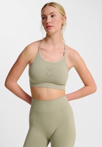 Olivgrön sport-bh med tunna remmar och rundad halsringning. Har ett subtilt chevronmönster i mitten. Matchas med högmidjade leggings.