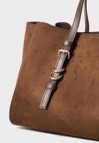 Braune Wildleder-Shopper-Tasche mit strukturiertem Finish und langem Trageriemen. Verfügt über goldene Hardware mit drei Ringen und kontrastierenden Steppnähten.