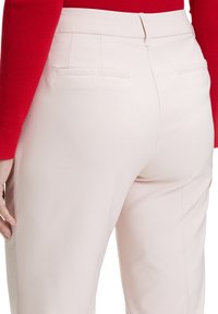 Pantaloni rosa chiaro realizzati in tessuto liscio, con frontale piatto, due tasche posteriori e una vestibilità su misura per un aspetto elegante.
