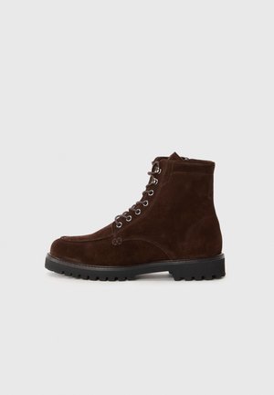 Bruine suedine veterschoenen met een robuuste zwarte zool, voorzien van zes veterogen en een gladde leren binnenkant. Medium hoogte ontwerp.