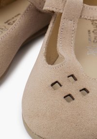 Zapatos de ante color tostado con punta redondeada, detalles recortados y acentos cosidos. Suela lisa y diseño ligero, adecuado para el uso diario.
