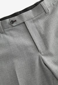 Pantalones de cuadros en gris con patrón de espiga, que cuentan con un frente plano, dos bolsillos laterales y un cierre de botón en la cintura. Textura de tela suave.