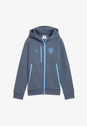Donkergrijze sportjas met capuchon, lichtblauwe ritsen en Manchester City- en Puma-logo's op de borst, plat liggend weergegeven op een witte achtergrond.