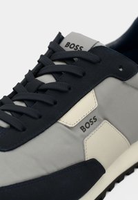 Mēteņu un pelēku sporta apavu ar zamšādu un auduma materiāliem. Ar noapaļotu purngalu, teksturētām auklām un "BOSS" zīmolu sānos.