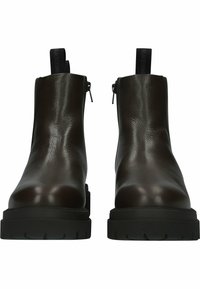 Botas de cuero marrón hasta el tobillo con un acabado brillante, suela plana de goma negra, cremalleras laterales y tiradores con un agarre texturizado.