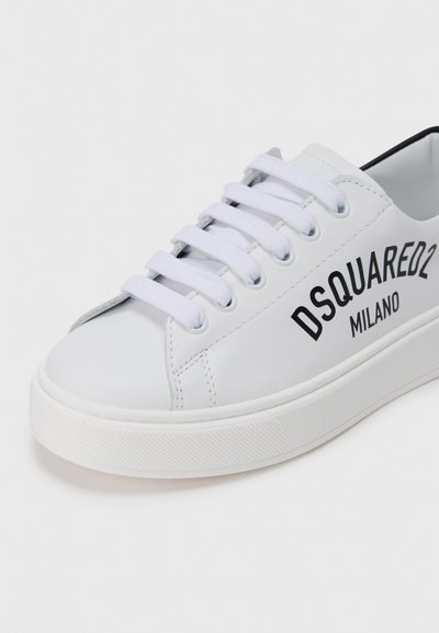 Baskets en cuir blanc avec bout rond, arborant un logo noir "DSQUARED2 MILANO", semelle en caoutchouc blanche texturée, et lacets plats blancs.