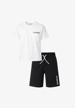 T-shirt bianca a maniche corte con taschino sul petto e logo nero, abbinata a pantaloncini neri con coulisse e logo bianco sulla gamba sinistra.