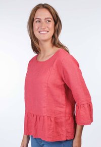 Rotes Leinenoberteil mit drei viertel langen Glockenärmeln und einem Rüschensaum. Hat einen runden Ausschnitt und zarte Spitzenverzierungen an den Ärmeln.