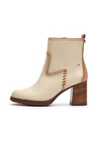 Beige leather ankle boot with a rounded toe, contrasting brown heel, and decorative stitching on the side. Textured wooden heel.