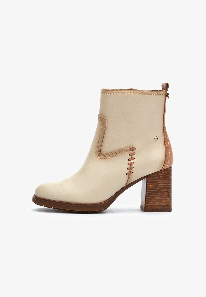 Botín de cuero beige hasta el tobillo con punta redonda, tacón marrón en contraste y costuras decorativas en el lateral. Tacón de madera texturizada.