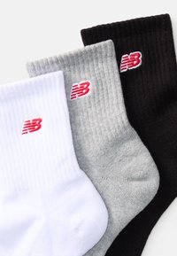 Conjunto de três meias de algodão de cano curto nas cores branca, cinza e preta, com textura canelada e logótipo da New Balance em vermelho bordado.