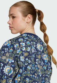 Sweatshirt s květinovým vzorem v námořnické modři, zdobený živými modrými a zelenými květy. Měkká textura s kulatým výstřihem a žebrovanými okraji.