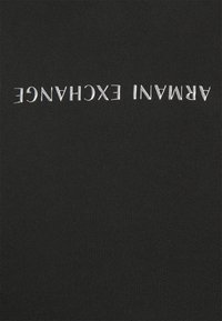Tela de ribete negro con texto plateado en relieve que dice "ARMANI EXCHANGE," orientado al revés. El material presenta una textura suave.
