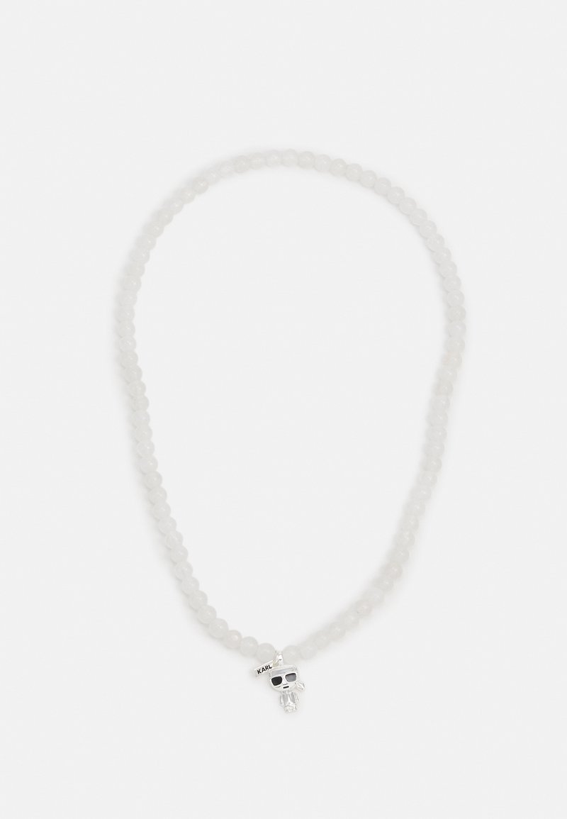 Collier de perles blanches avec un pendentif crâne en argent portant des lunettes de soleil et une petite étiquette portant l'inscription "KARL."