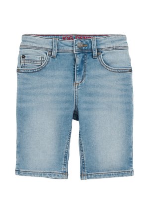 Bambino che indossa una maglietta verde oliva con stampa di palme, pantaloncini di jeans azzurri risvoltati e sneaker beige con lacci bianchi, in piedi su un pavimento neutro.