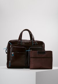 Briefcase in pelle marrone con accenti blu, dotato di più tasche e una borsa in tessuto marrone rimovibile. Texture liscia e design strutturato.