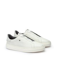 Las zapatillas de piel blancas presentan un diseño de caña baja con bandas elásticas para un fácil uso, costuras sutiles y un patrón texturizado en la parte superior.