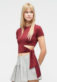 Tumesinine kõhukate laiendatud sõlmega küljel, lühikeste varrukatega ja ümmarguse kaelusega, koos helehallide volditud seelikuga.