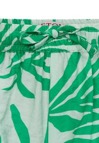 Pantaloni corti verdi e bianchi con motivo, dotati di una vita elasticizzata e dettagli con fiocco. Realizzati in tessuto leggero con una texture morbida.