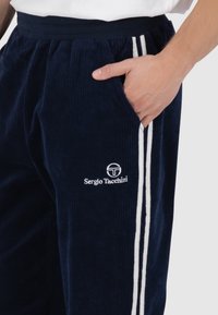 Navy corduroy broek met witte zijstrepen, met een koord in de taille en geborduurd logo op de dij. Getextureerde stof met zakken.