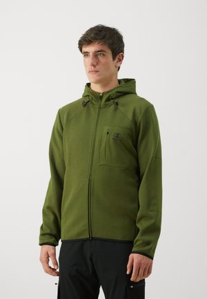 Grüne Zip-Hoodie mit tailliertem Schnitt, Kapuze und Fronttasche. Hergestellt aus einem strukturierten Stoff mit schwarzen Akzenten und Logo auf der Brust.