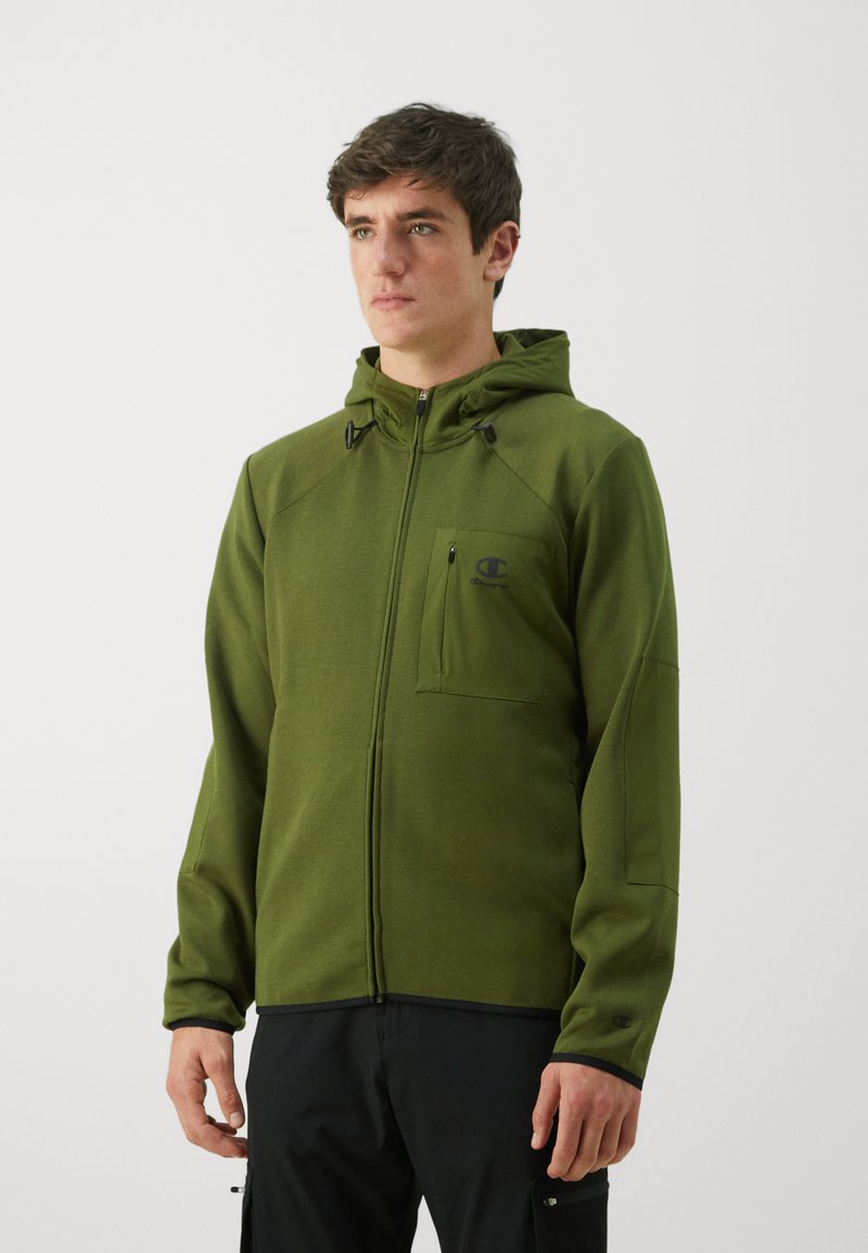 Grüne Zip-Hoodie mit tailliertem Schnitt, Kapuze und Fronttasche. Hergestellt aus einem strukturierten Stoff mit schwarzen Akzenten und Logo auf der Brust.