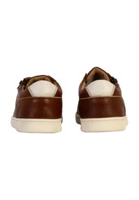 Chaussures en cuir marron avec une finition texturée, accents blancs et profil bas. Présentent un léger talon et un col rembourré.