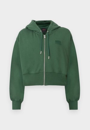Haut court vert avec zip à l'avant, capuche à cordon de serrage et poignets côtelés. Tissu lisse avec un petit badge logo sur la poitrine.