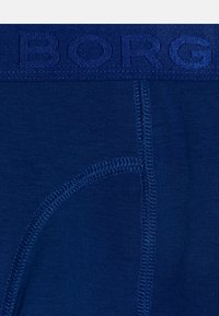 Boxer shorts para hombres en azul marino, hechos de un tejido suave, con una cinturilla texturizada que tiene "BORG" bordado. Las costuras planas proporcionan bordes suaves.