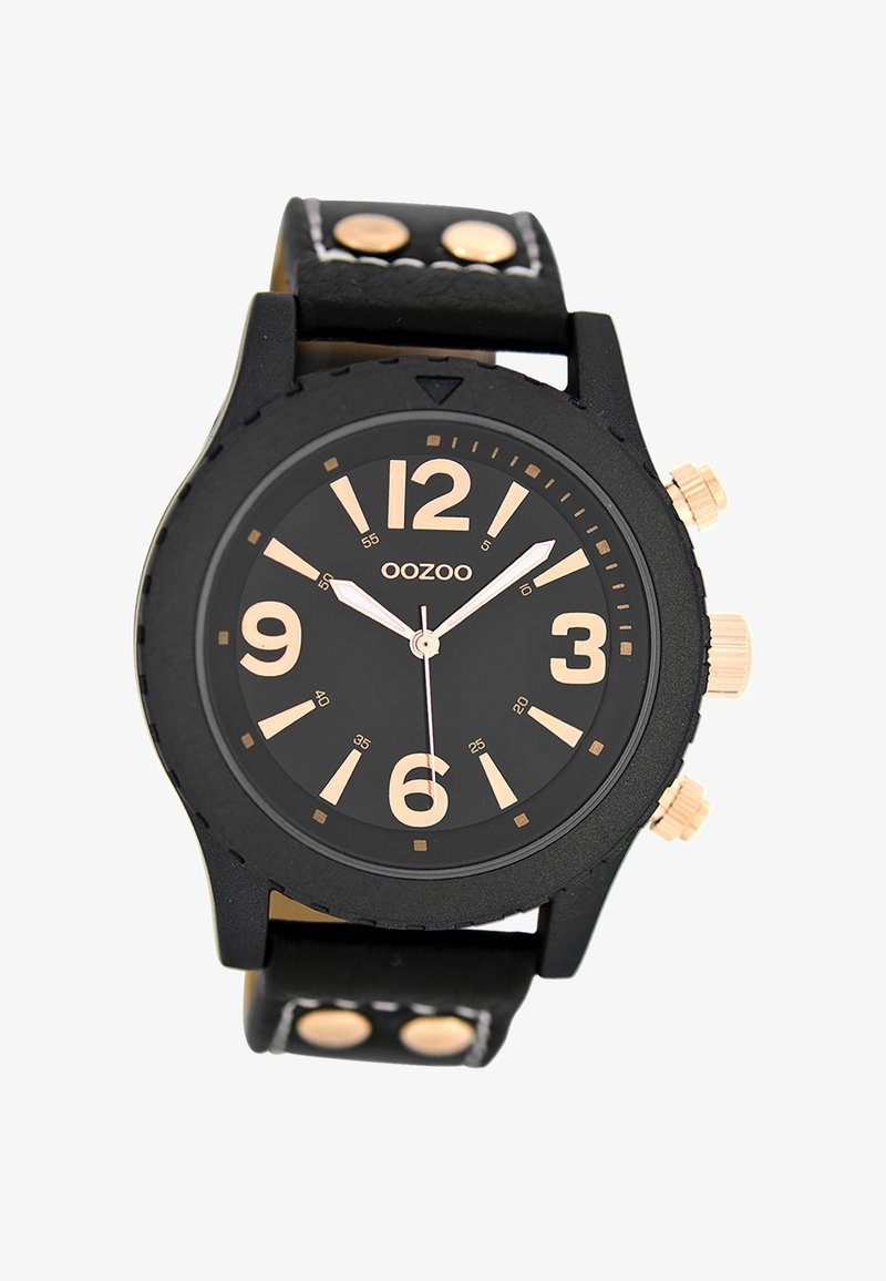 Montre noire avec un cadran rond, des chiffres dorés et trois boutons sur le côté. Elle possède un bracelet en cuir noir texturé avec des accents dorés.