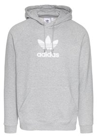 Šedá mikina s kapucí z měkké tkaniny s přední kapsou, obsahující bílé logo trefoil a text "adidas" pod ním. Obsahuje šňůrku pro nastavení kapuce.