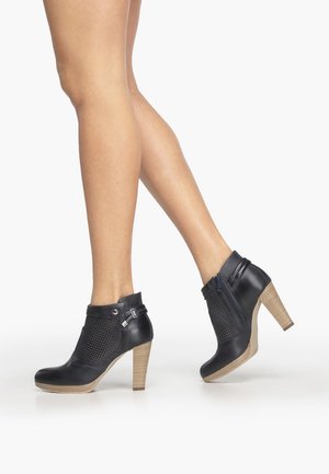 Bottes basses noires avec un panneau en mesh texturé, un bout arrondi et un talon en bois. Dotées d'une fermeture éclair latérale et de détails décoratifs.