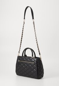 Borsa a tracolla trapuntata nera con una forma strutturata, doppio manico superiore, una tracolla a catena removibile e una tasca frontale con cerniera e hardware dorato.