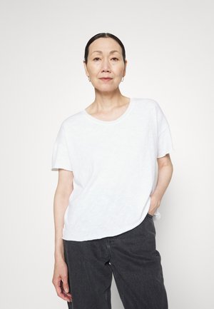 Witte t-shirt met korte mouwen, gemaakt van een gestructureerde stof, met een relaxte pasvorm en een ronde hals. Gecombineerd met donkere broeken.
